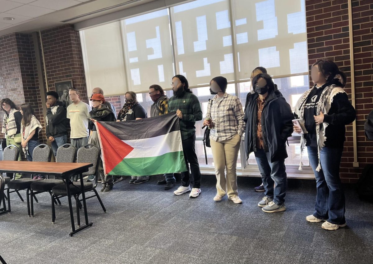Students hold a Palestinian flag during a demonstration by Students for Justice in Palestine at a UCOSA meeting where a resolution urging the UCO Foundation to divest from certain companies was discussed. Photo provided by Soha Jawaid.
